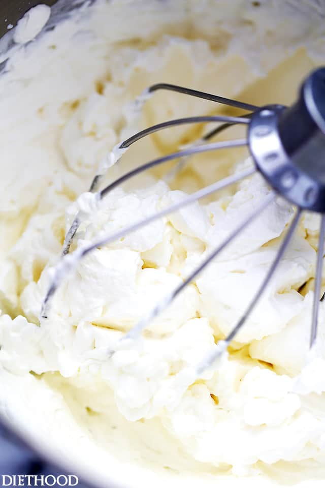 A mixer's whisk in a bowl, whisking around to make whipped cream.