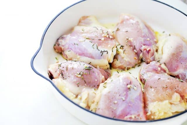 Chicken seasoned with rosemary in a skillet.
