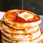 Pouring syrup over buttermilk pancakes.