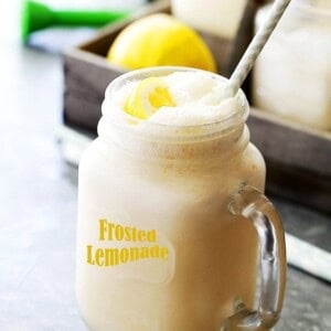 A glass jar filled with frosted lemonade with a straw.