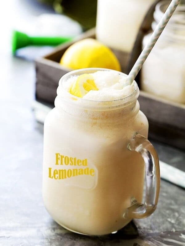 A glass jar filled with frosted lemonade with a straw.