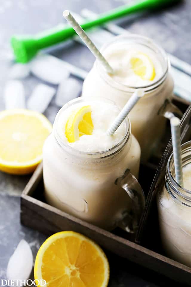 Two glass jars filled with frosted lemonade with straws in a black tray.