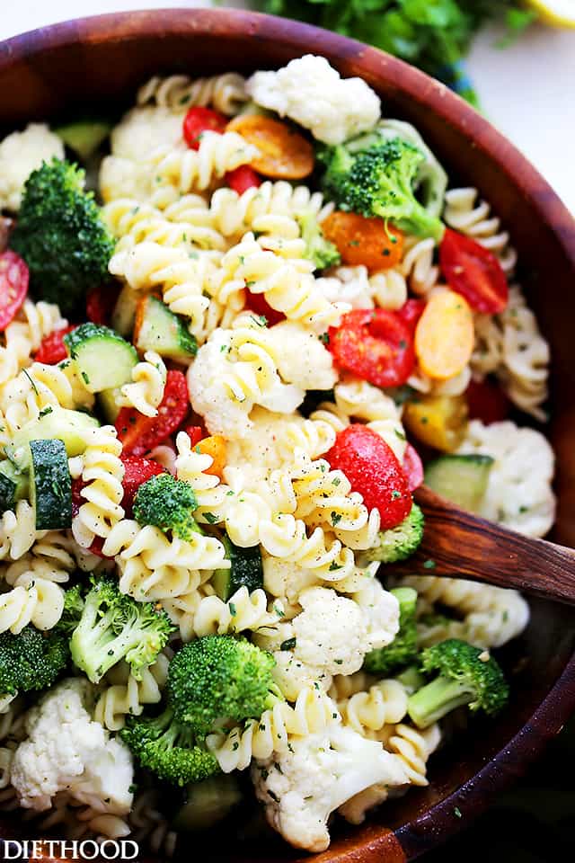 A close up of pasta salad that has broccoli, cauliflower, tomatoes and cucumbers in it