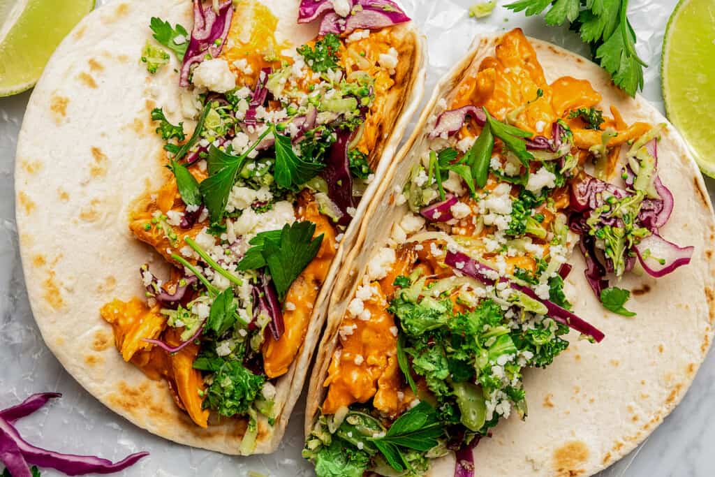 Two tacos filled with buffalo chicken and other toppings.