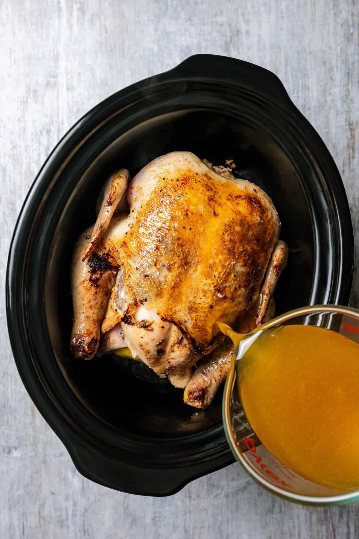 Crock pot honey lemon chicken is an easy dinner with a whole chicken slow-cooked in a citrusy honey lemon sauce with butter and seasonings. Honey lemon marinade being poured over a whole chicken inside the crock pot.