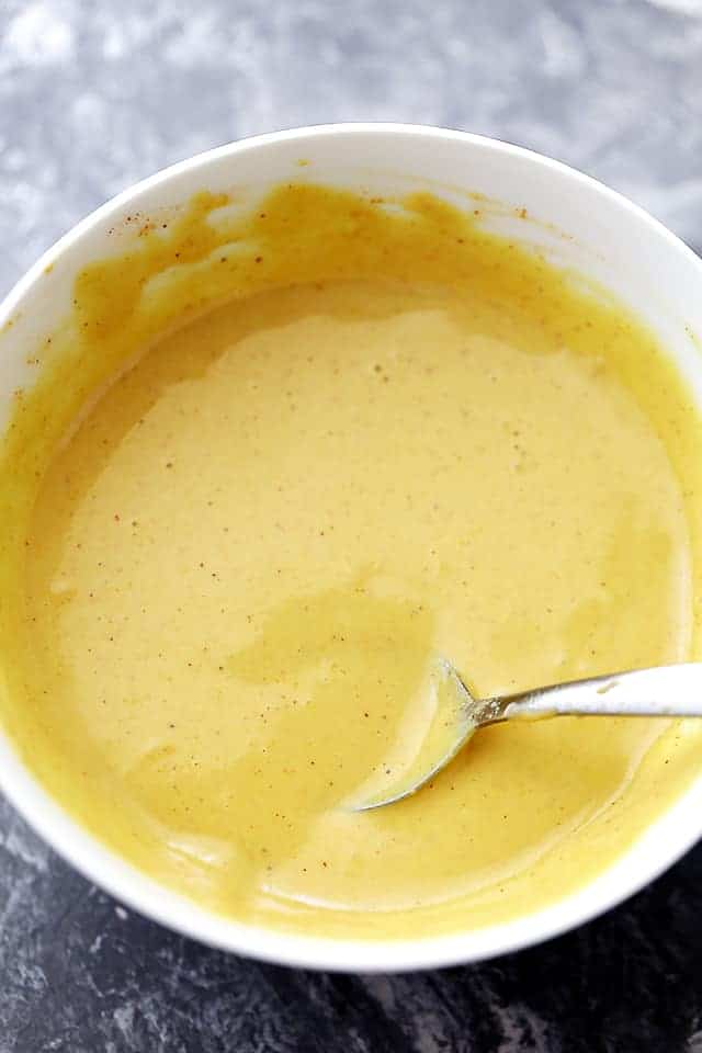 Homemade Honey Mustard Sauce in a small white bowl with a spoon placed in the sauce.