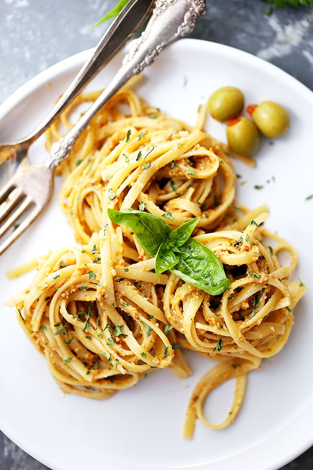 Olive Pesto Pasta nests arranged on a white dinner plate with a fork placed near the pasta.