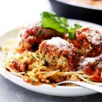 Ricotta Zucchini Meatballs served on a dinner plate and topped with tomato sauce and parmesan cheese.