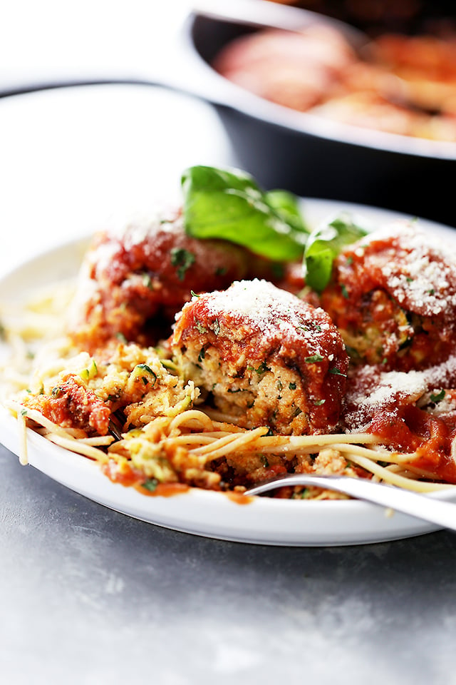 Ricotta Zucchini Meatballs served on a dinner plate and topped with tomato sauce and parmesan cheese.