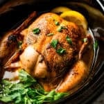 A cooked whole chicken inside the crock pot.