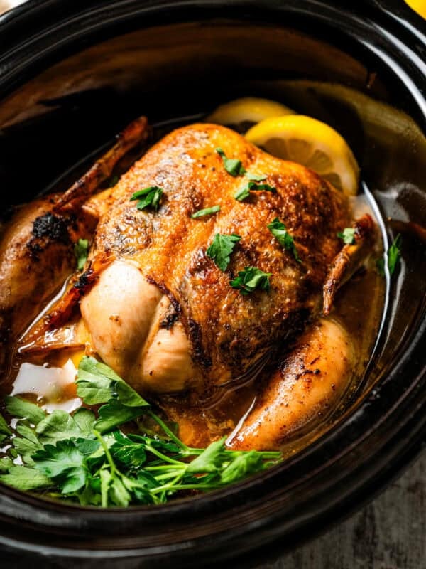 A cooked whole chicken inside the crock pot.