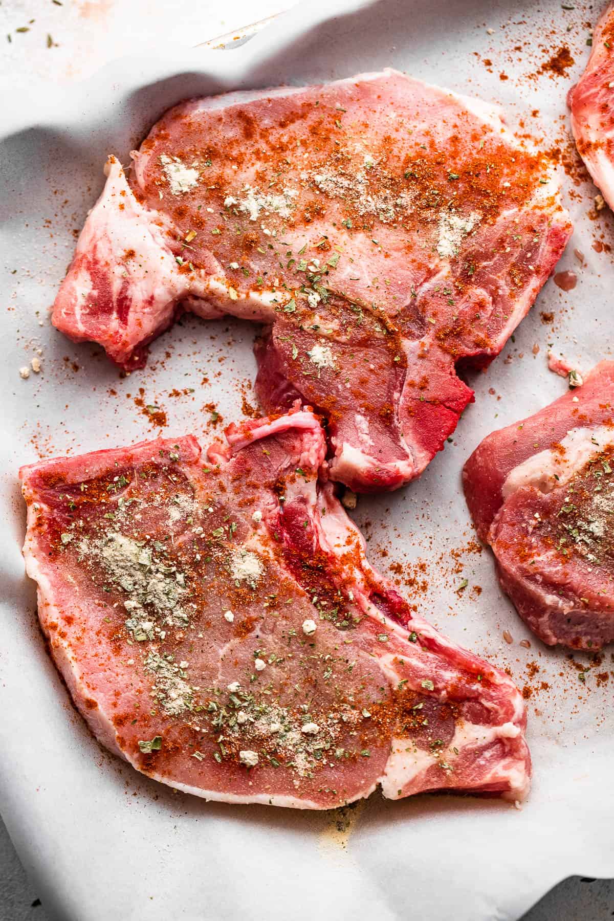 Four raw pork chops on parchment paper.