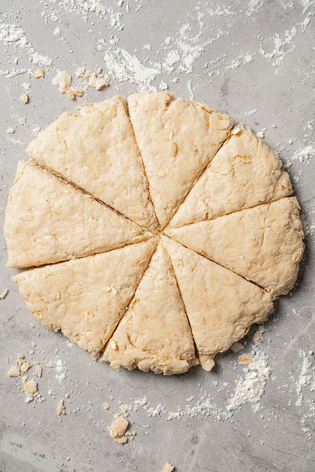 Scone dough shaped into a disc and cut into wedges on a floured countertop.