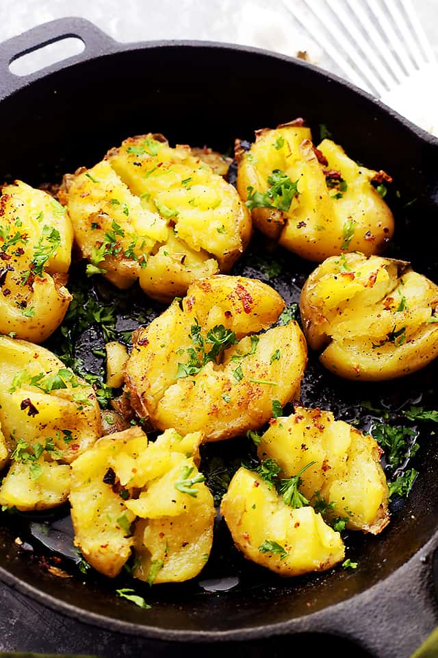A close up of seasoned Smashed Potatoes in a cast iron skillet
