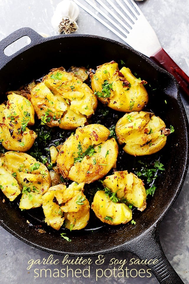 A bunch of potatoes smashed with seasonings in a cast iron skillet
