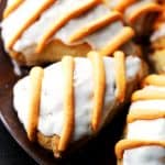 Close up image of pumpkin pie spice scones finished with a glaze and icing drizzle, arranged on a plate.