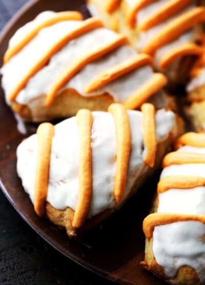 Close up image of pumpkin pie spice scones finished with a glaze and icing drizzle, arranged on a plate.