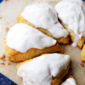 An assortment of glazed pumpkin spice scones on a baking sheet.