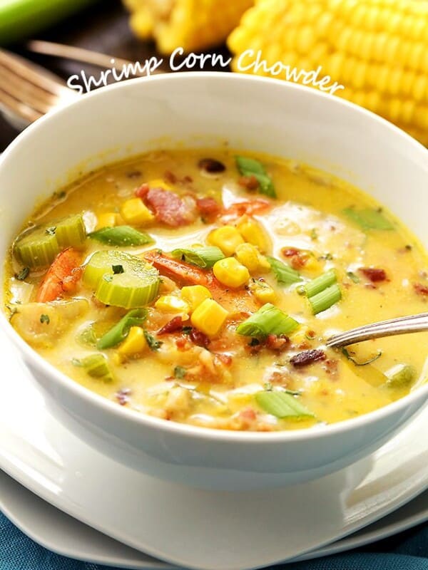 A white bowl filled with creamy chowder. Corn, shrimp, celery, and bacon are in the chowder.