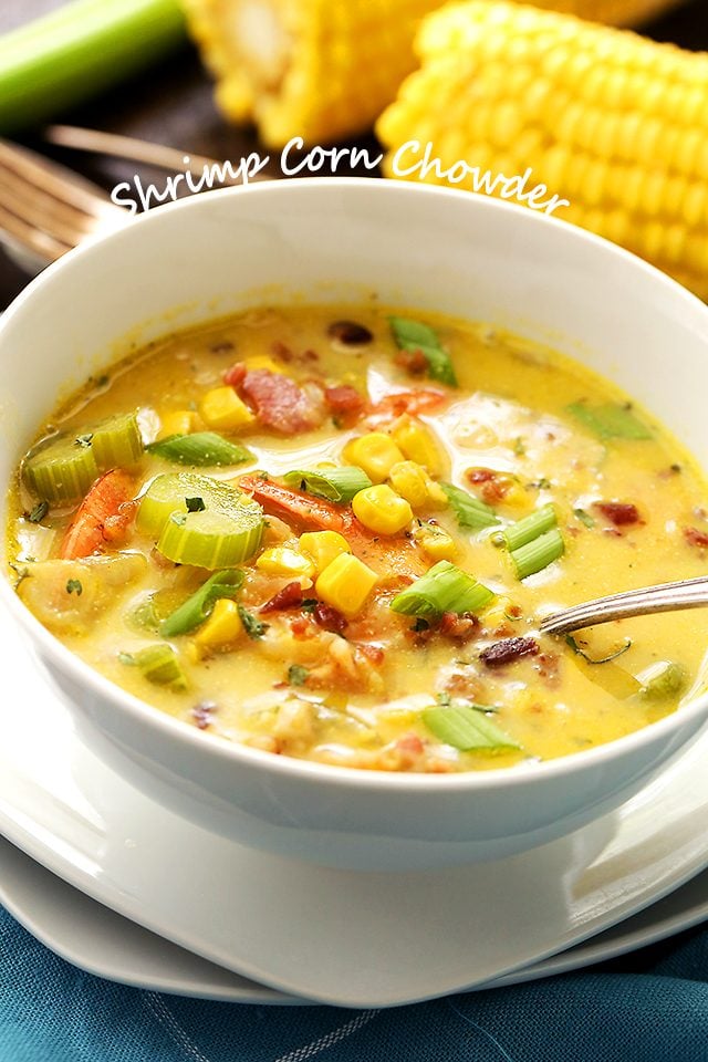 A white bowl filled with creamy chowder. Corn, shrimp, celery, and bacon are in the chowder.