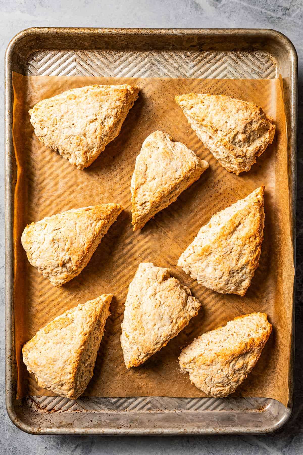 Baked cinnamon scones on a parchment-lined baking sheet.