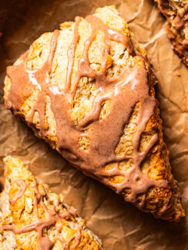 Overhead close-up of a glazed cinnamon scone set on a sheet of brown paper.