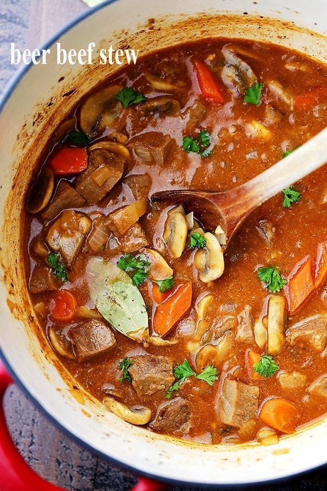 Overhead image of beef stew in a Dutch oven with a wooden spoon stirring through it.
