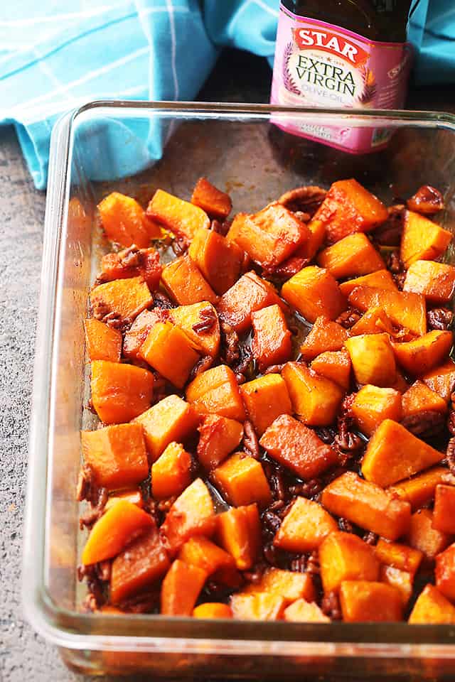 Honey roasted butternut squash in a baking dish next to a bottle of Star Foods Extra Virgin Olive Oil