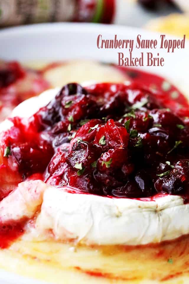 A wheel of melted baked brie cheese topped with red cranberry sauce.