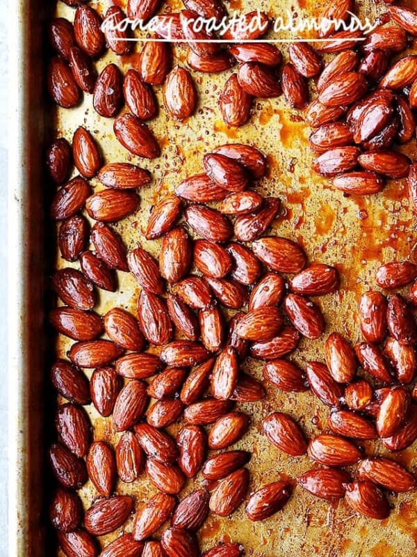 Overhead view of honey roasted almonds on a parchment-lined baking sheet.