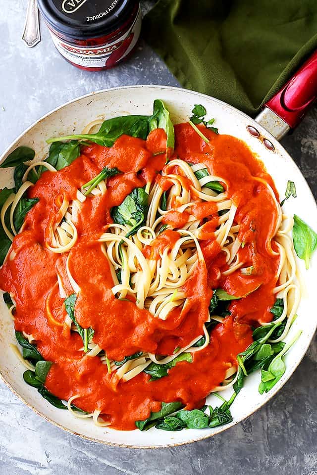 Overhead view of red pepper pasta sauce served over a bowl of linguine.