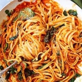 A skillet with Red Pepper Sauce Pasta with Spinach and Feta.