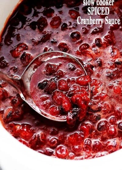Spiced Cranberry Sauce is ladled from a crock pot bowl.