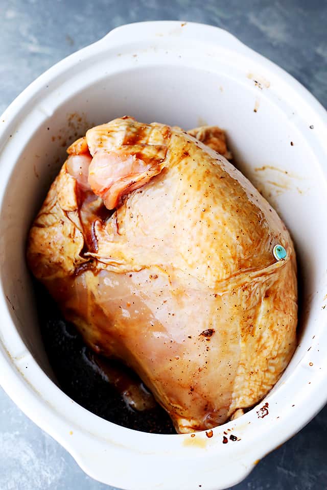 A whole turkey breast placed in a slow cooker along with a spiced honey-soy marinade.