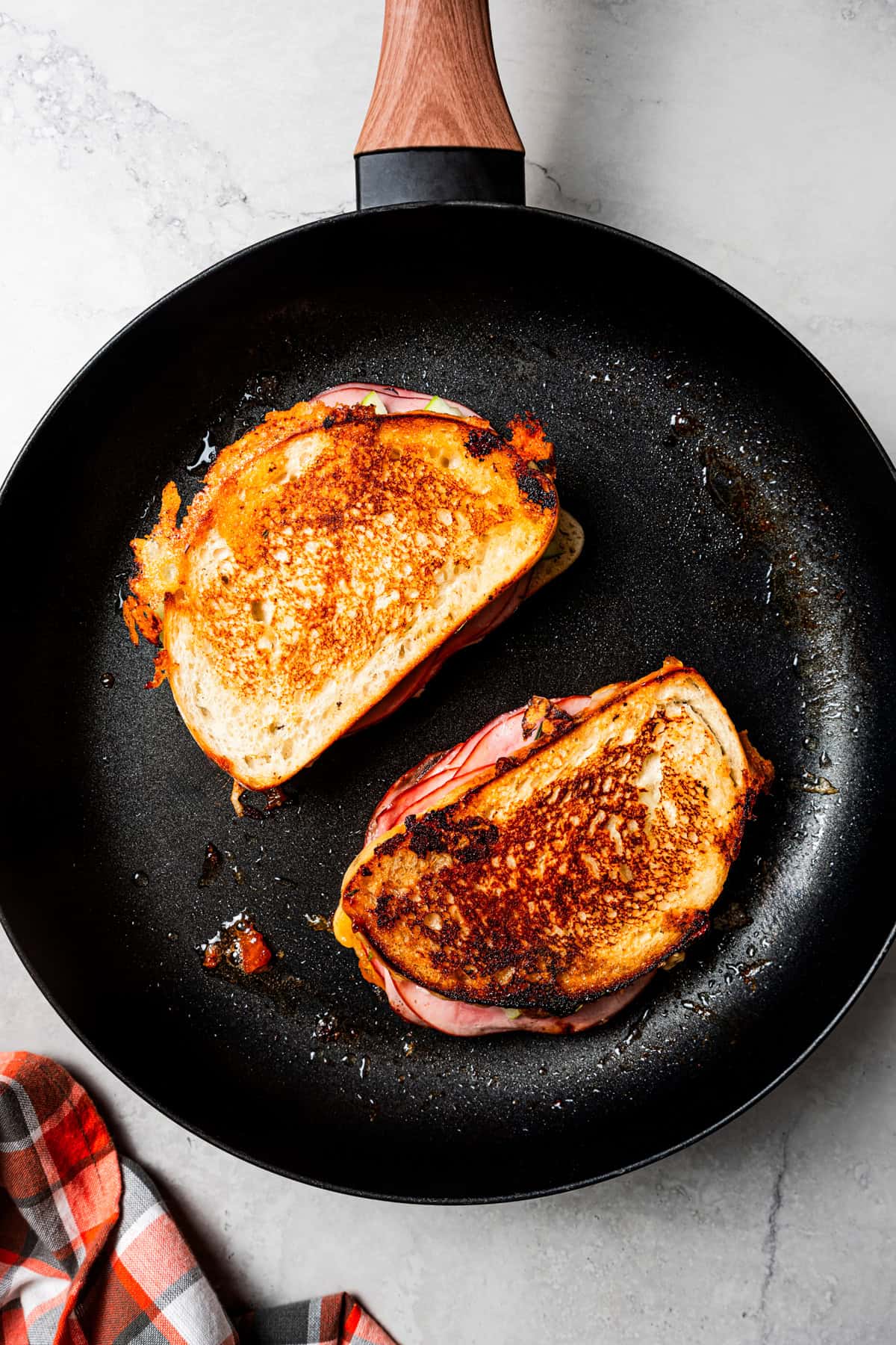 Two grilled cheese sandwiches toasting in a skillet.