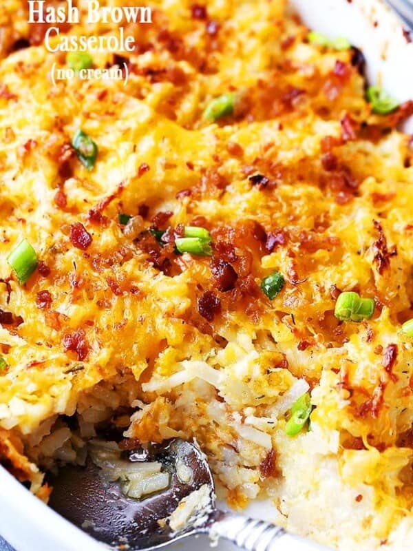 Close up of hash brown casserole in an oval baking dish with a serving missing from the corner.