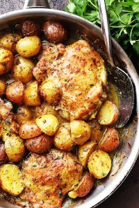 Chicken thighs and Potatoes in a pan.