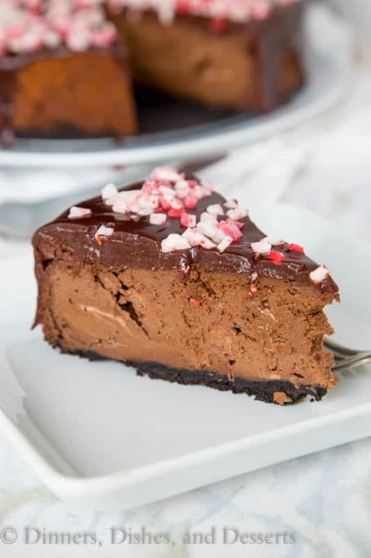 A slice of chocolate cheesecake topped with peppermint on a plate