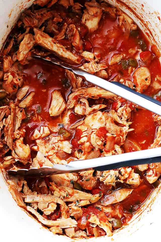 Mixing shredded chicken into a red sauce.