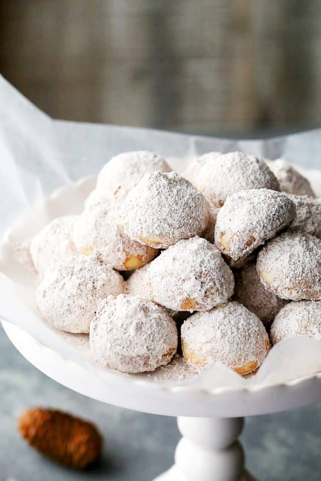 Chai Spiced Snowdrop Cookies are arranged on a white porcelain cake stand.