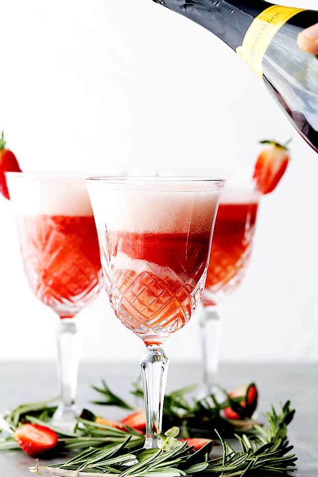 A Rossini cocktail topped up with Prosecco, with two more glasses in the background.