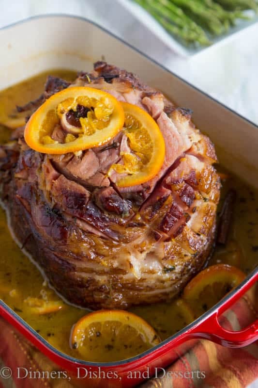 Glazed ham with tangerine slices in a roasting pan