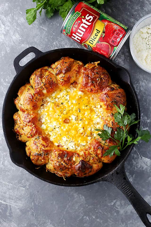 Overhead view of soft and buttery pull apart rolls baked around a warm feta cheese dip in a cast iron skillet