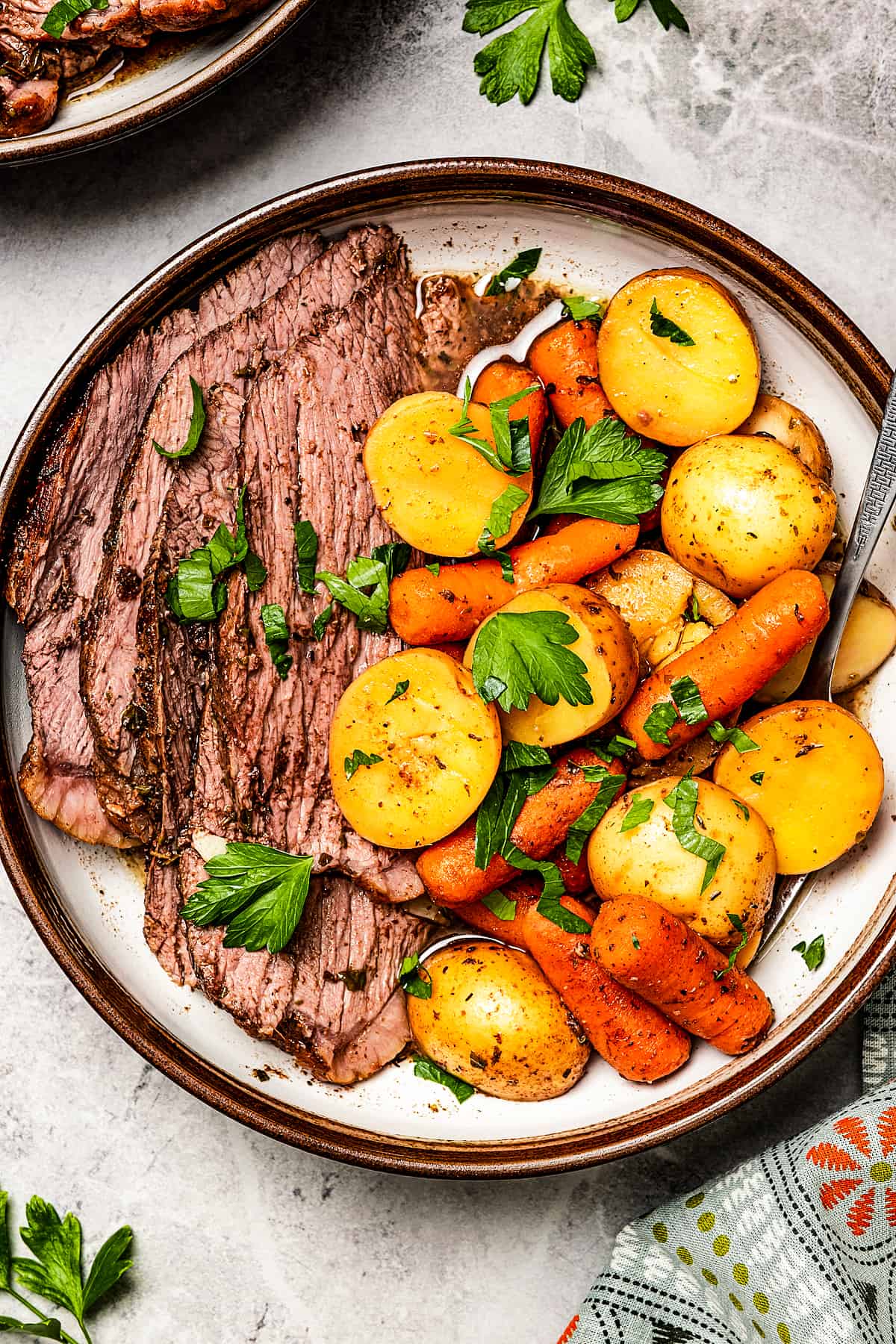 Sliced roast beef with potatoes and carrots on a dinner plate.