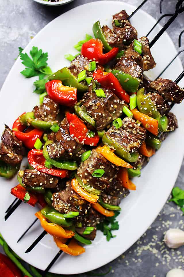 Asian beef skewers with vegetables on a plate.