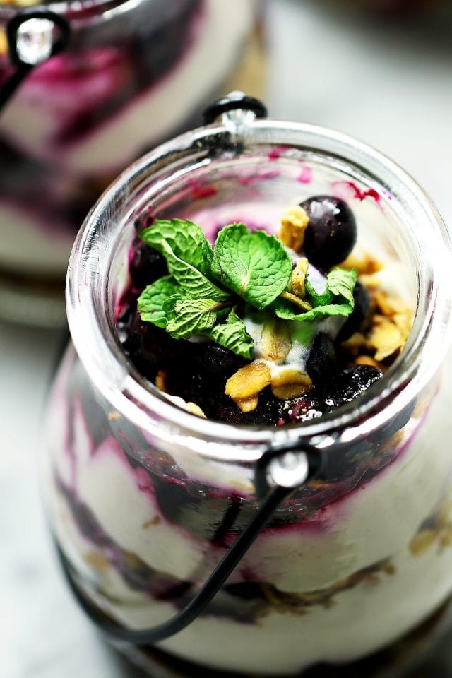 No Bake Skinny Blueberry Cheesecake Parfaits - Delicious layers of lightened-up creamy and lemony cheesecake filling, sweet granola, and a homemade blueberry sauce.