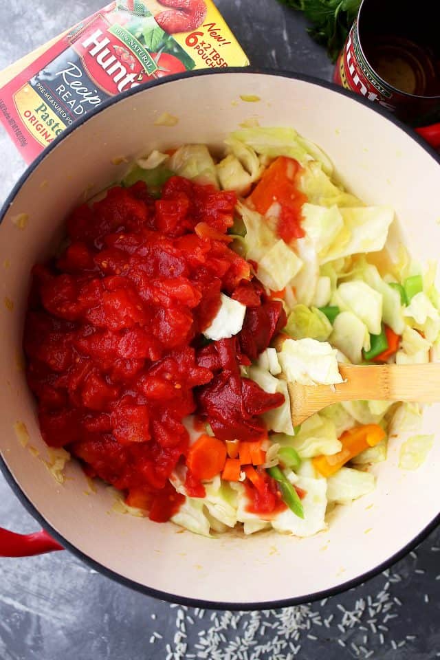 Adding diced tomatoes and tomato paste to cabbage soup.