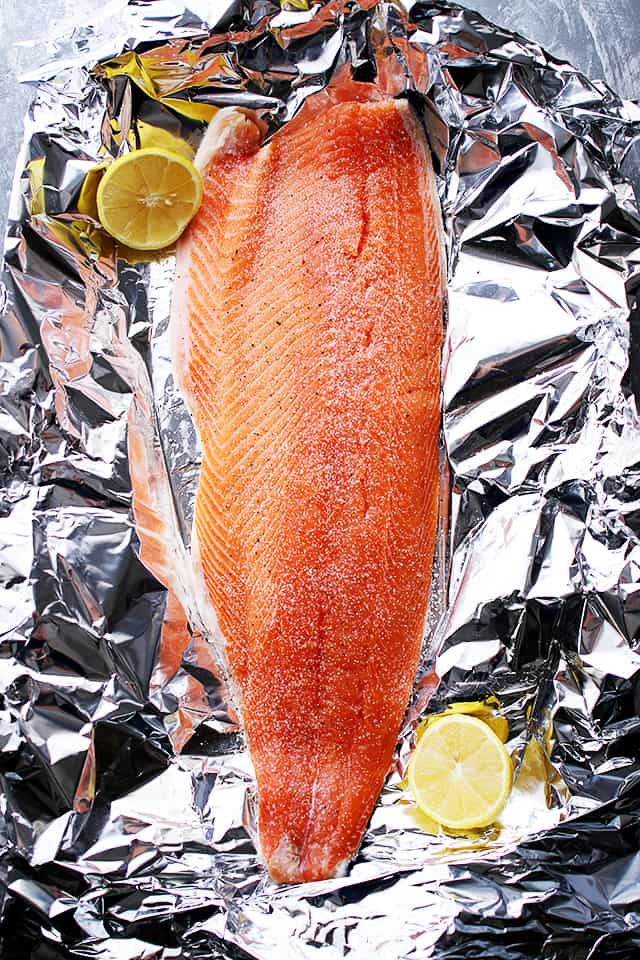 A whole salmon fillet is placed on a piece of aluminum foil.