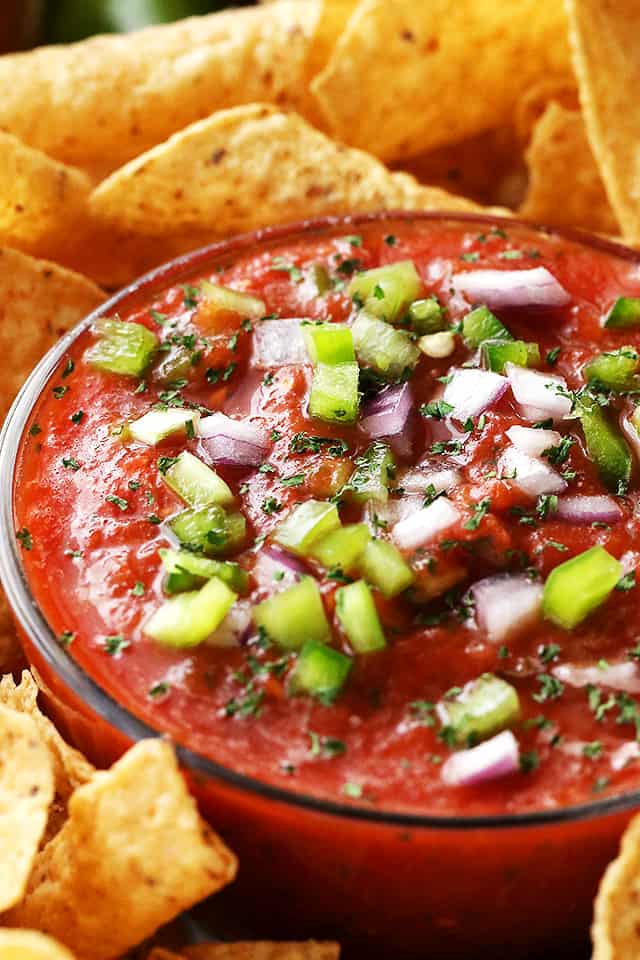 Close-up photo of tomato salsa topped with diced green peppers and onions.