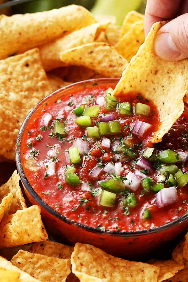 Homemade Salsa served in a bowl and garnished with diced peppers and red onions.